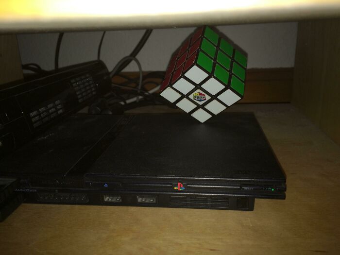 Wild and unhinged way to fix a tilted PlayStation 2 console with a Rubiks Cube to level it.