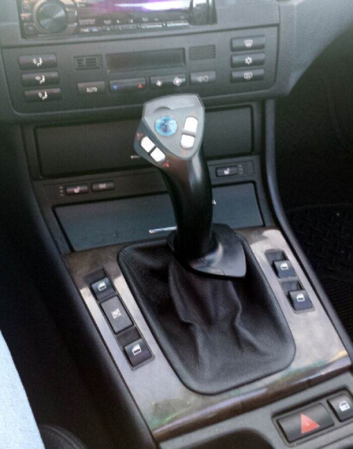 A car interior featuring a joystick as a gear shifter, an unhinged way to fix something.