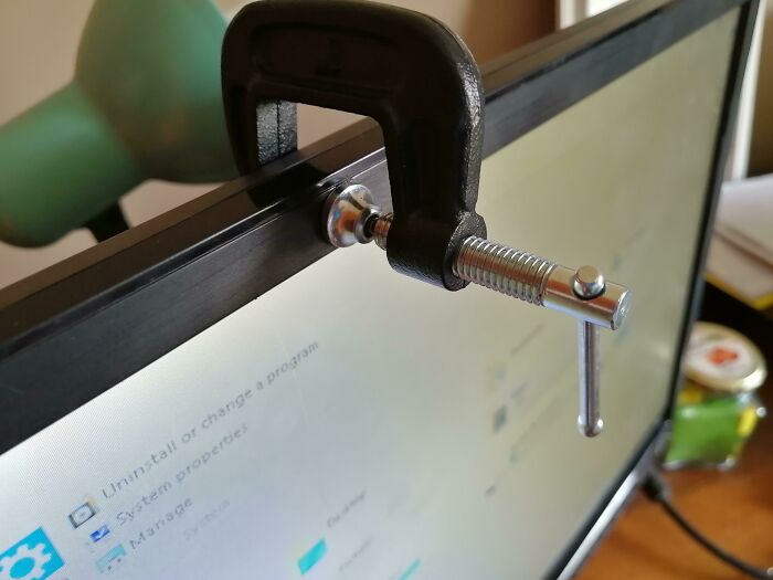 A C-clamp used to fix something by holding a computer monitor together, showing unhinged ways to fix.