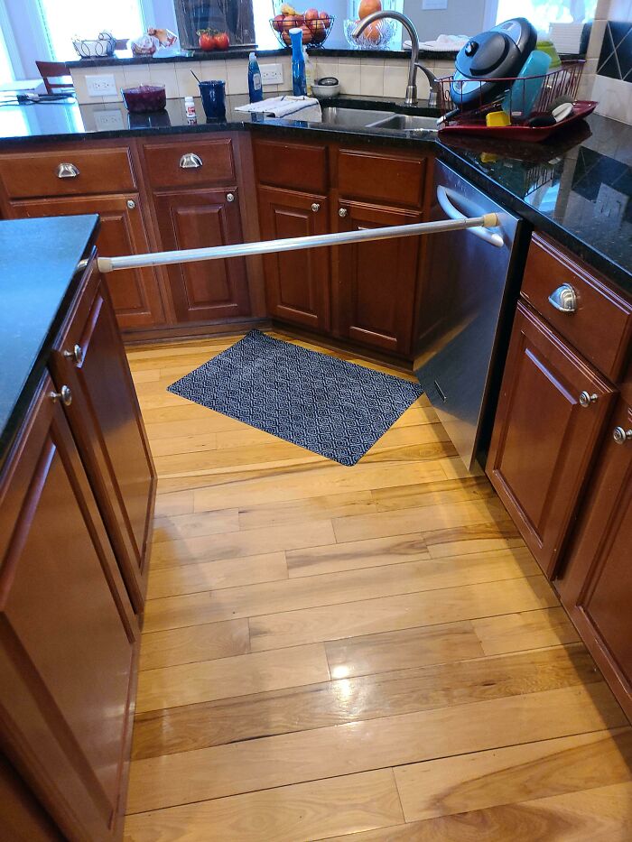 A wild and unhinged way to fix a cabinet with a tension rod in a kitchen.