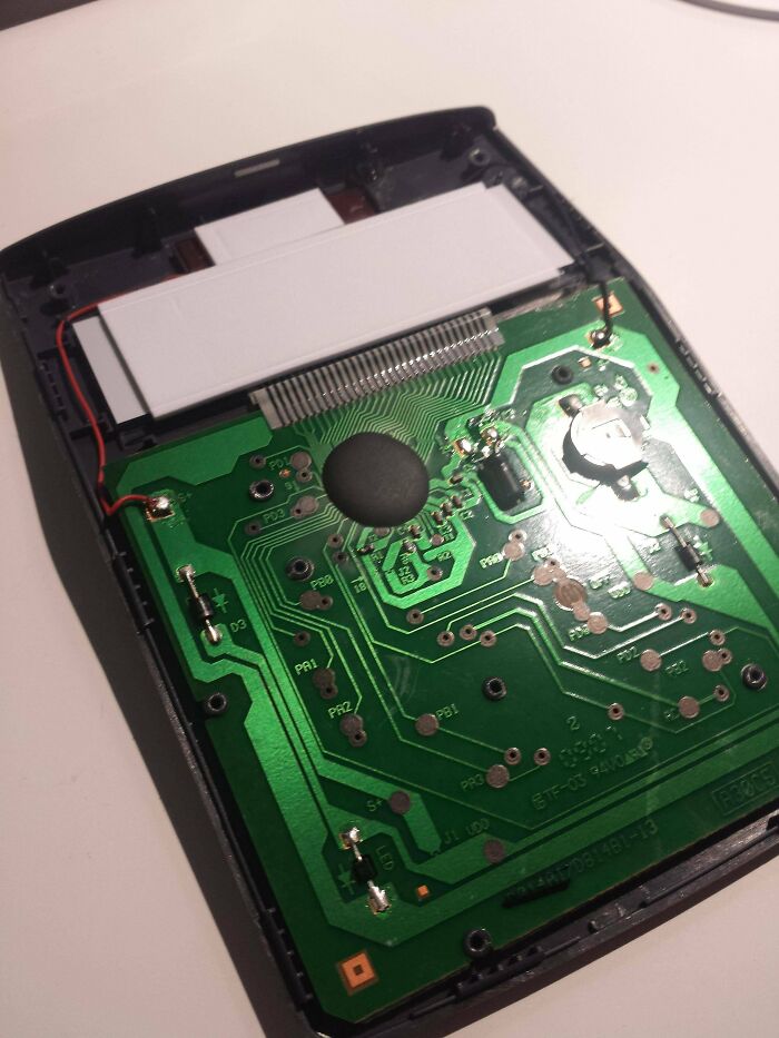 A wild and unhinged way to fix a calculator, with its back cover off revealing the circuit board.