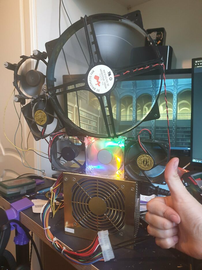 A person gives a thumbs-up to a wild, unhinged PC cooling system with multiple fans and a power supply.