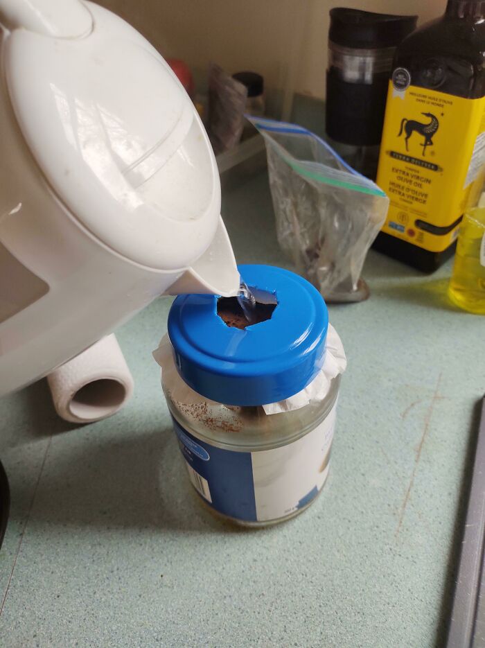 Hot water being poured into a jar through a makeshift hole in the lid, showing a wild and unhinged way to fix something.