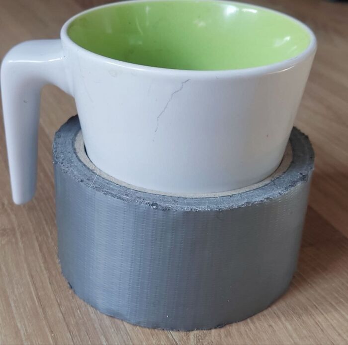 A white mug with a green interior placed on a roll of grey duct tape, a wild and unhinged fix.
