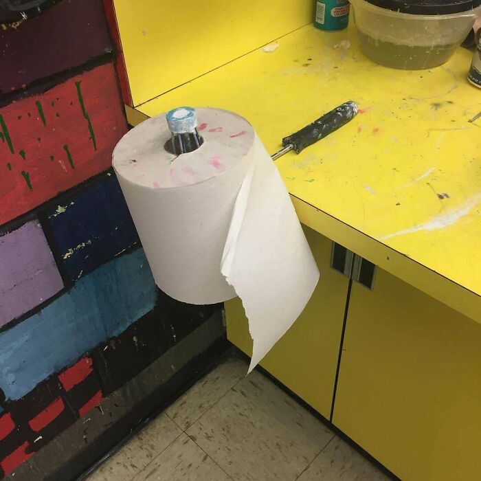A roll of paper towels held by an unhinged paint roller handle, showing a wild way to fix something.