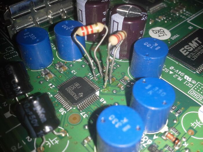 Close-up of a circuit board with resistors, capacitors, and a chip, displaying unhinged ways to fix something.