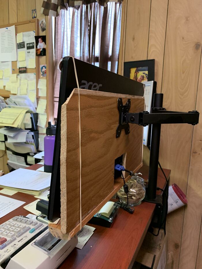 Wild and unhinged way to fix a monitor mount using wooden boards and rubber bands.