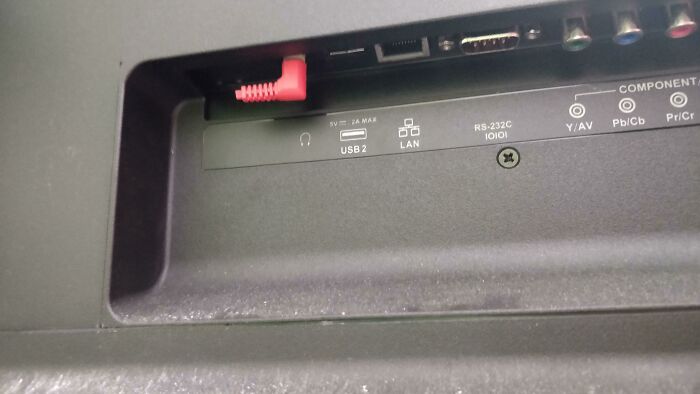 A red audio jack bent and inserted into a USB 2 port, exemplifying wild and unhinged ways to fix something.