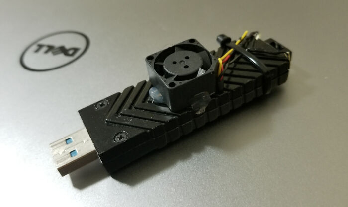 A USB drive with a miniature fan attached for cooling, a wild and unhinged way to fix something.