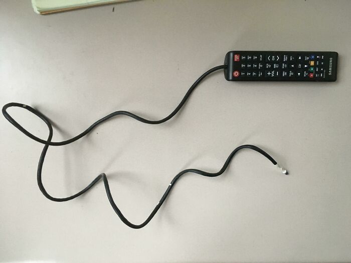 A Samsung remote control is attached to a long, winding cable, an unhinged way to fix something.