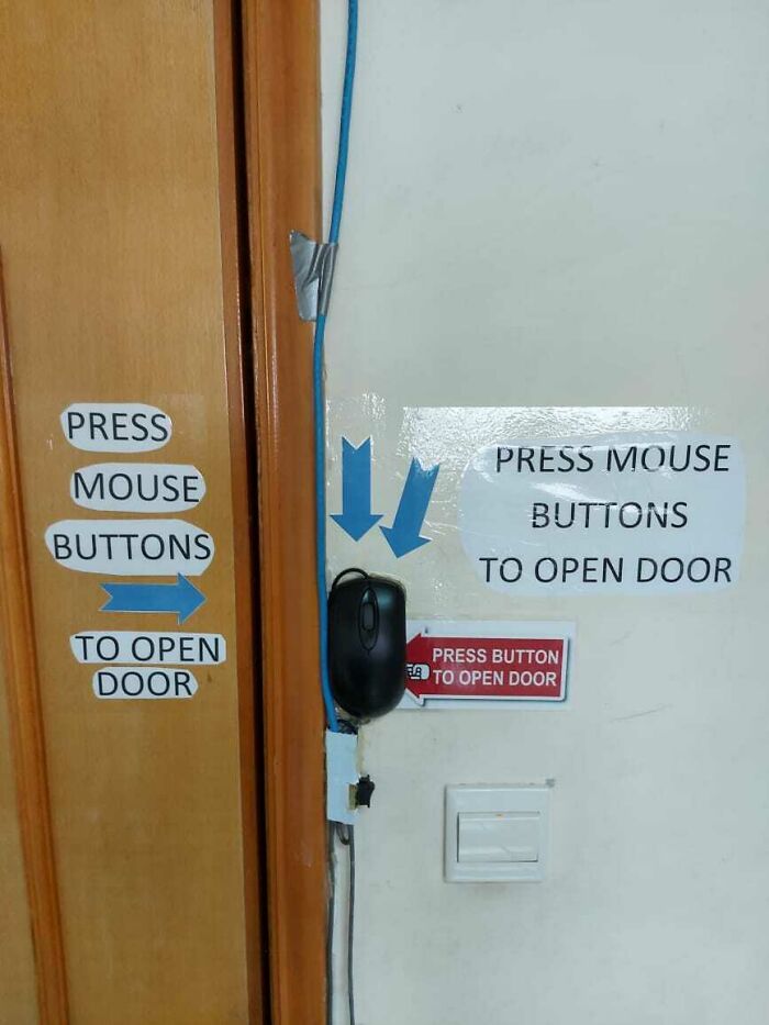 A computer mouse is taped to a wall, serving as a door opener, a wild way to fix something.