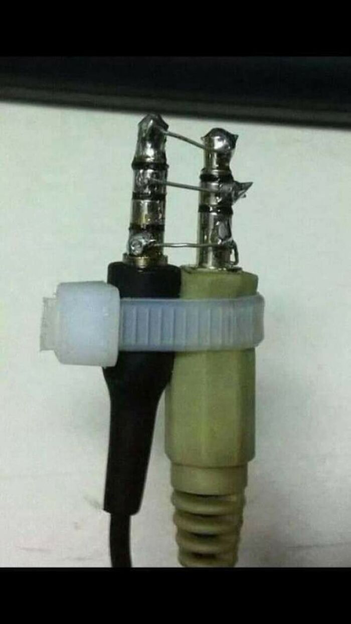 Two audio jacks crudely connected with wire and plastic, a wild way to fix a missing adapter.