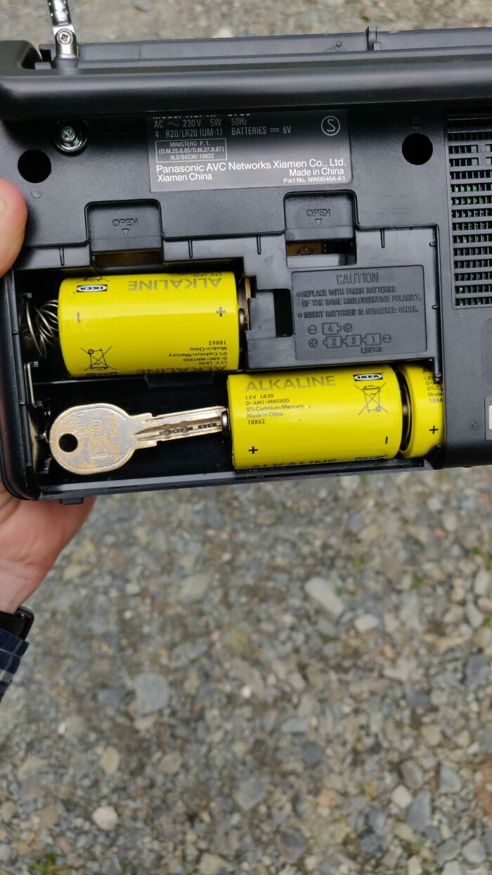 Wild and unhinged fix: a house key used as a spacer in a radio battery compartment.