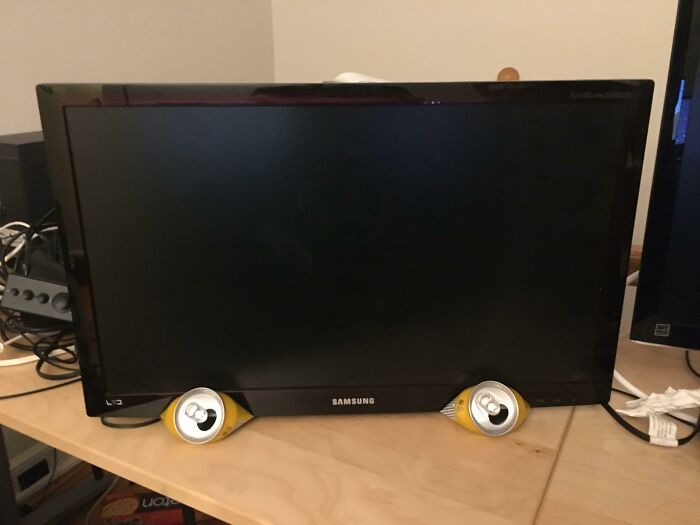 Wild and unhinged way to fix a Samsung monitor propped up by two empty soda cans.