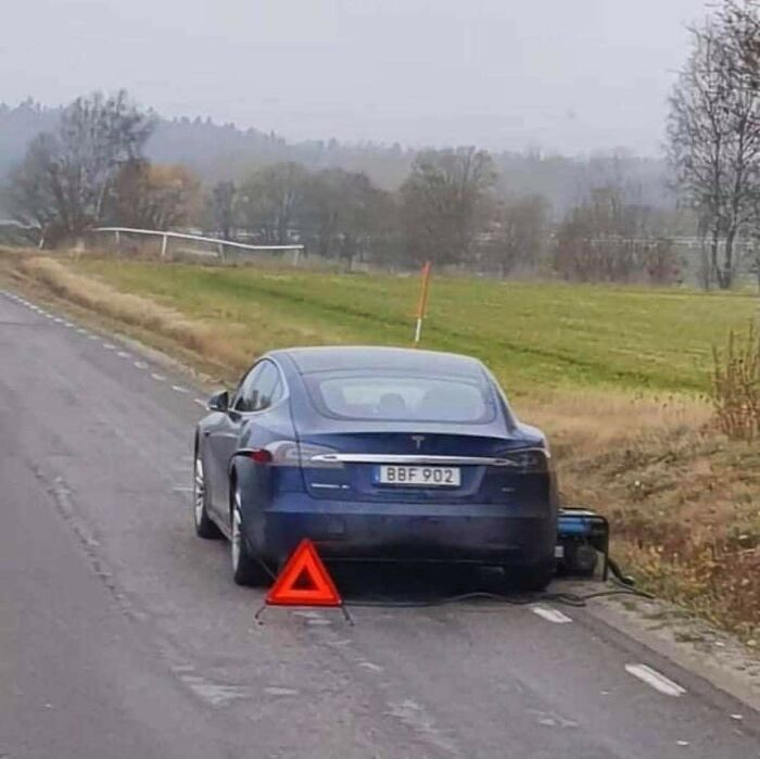 Wild and unhinged way to fix a blue Tesla charging on the side of a road with a caution triangle.