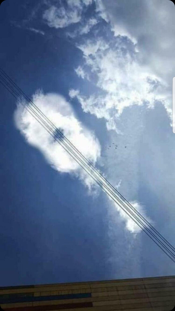A guitar-shaped cloud in a blue sky, an incredibly dumb pun on music.
