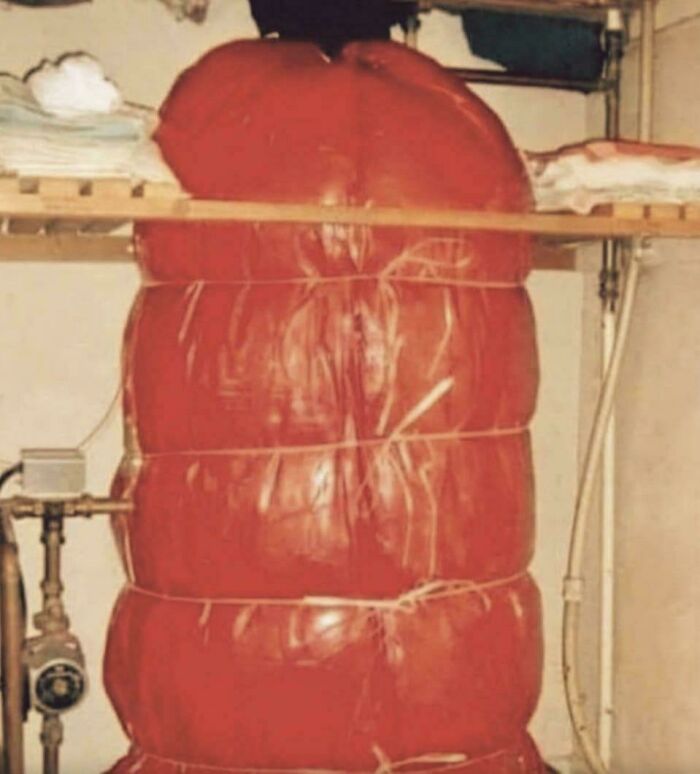 A large, red, inflated bag tied with string, possibly an old water heater or storage, from life in the 80s.