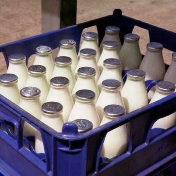 A blue crate filled with glass milk bottles with silver caps, evoking good memories of life in the 80s.