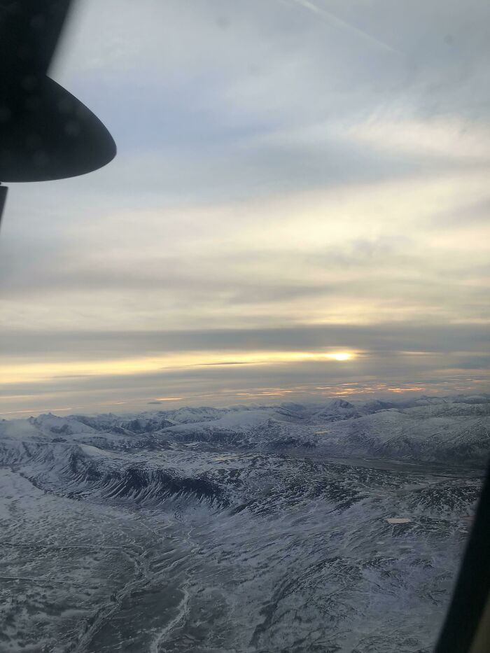 An aerial view of snowy mountains with a sunset, a photo you need to look twice at to understand.