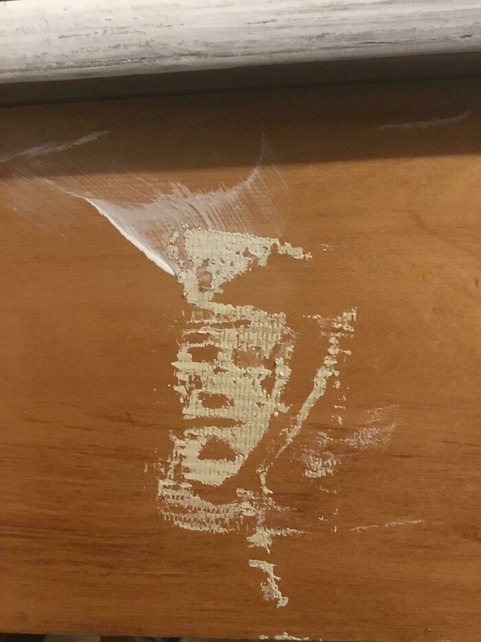 Paint peeling off wood resembling a face, a photo you need to look twice at to understand.