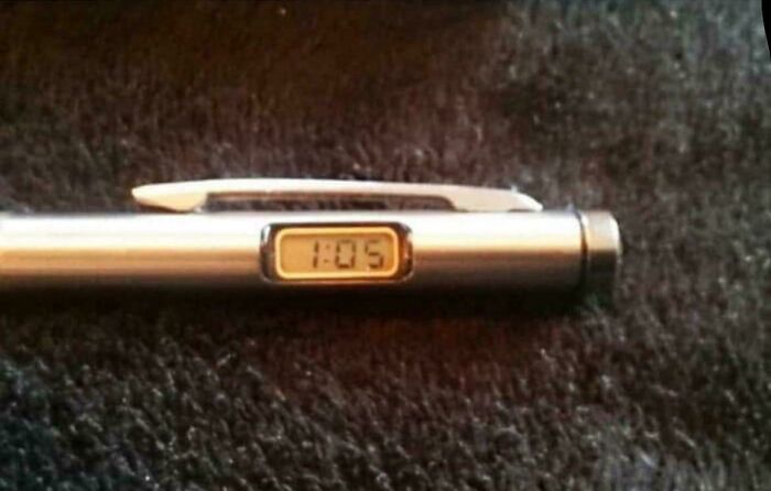 A close-up of a pen with a small digital clock displaying 1:05, a gadget from good memories of life in the 80s.