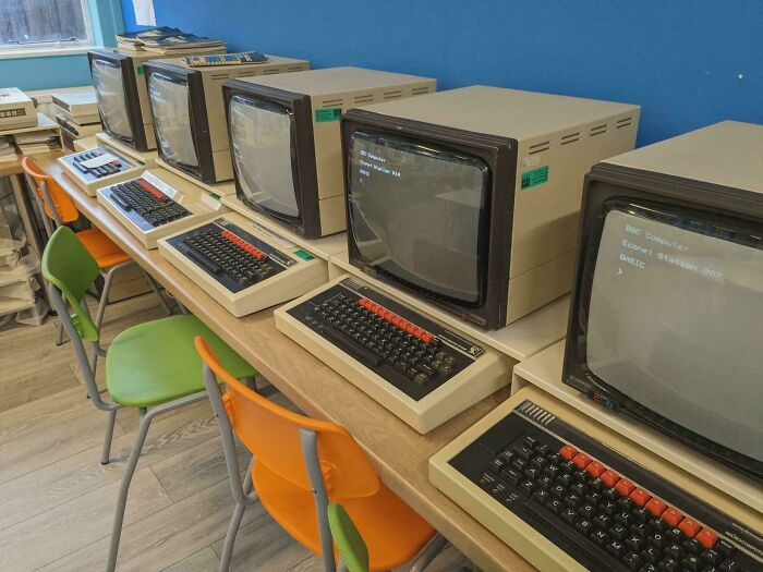 A row of vintage BBC Micro computers in a classroom, showcasing life in the 80s.
