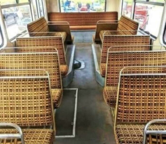 An empty interior of a bus with patterned seats, evoking good memories of life in the '80s.