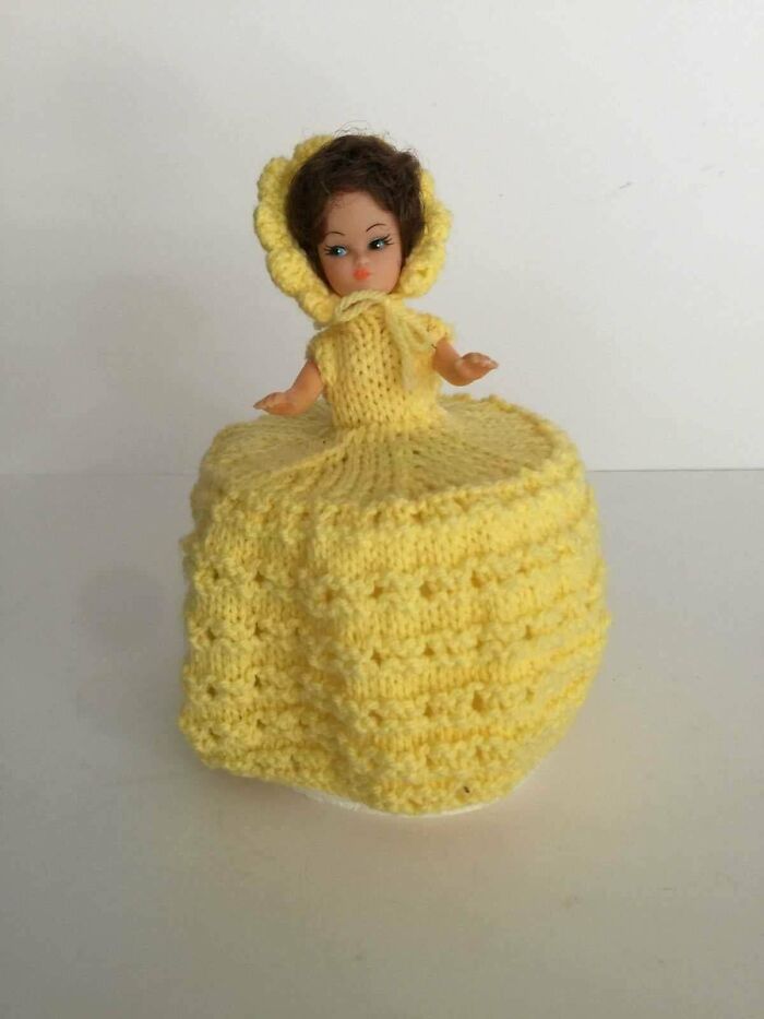 A toilet paper doll from the 80s with a yellow knitted dress and bonnet, bringing back good memories.