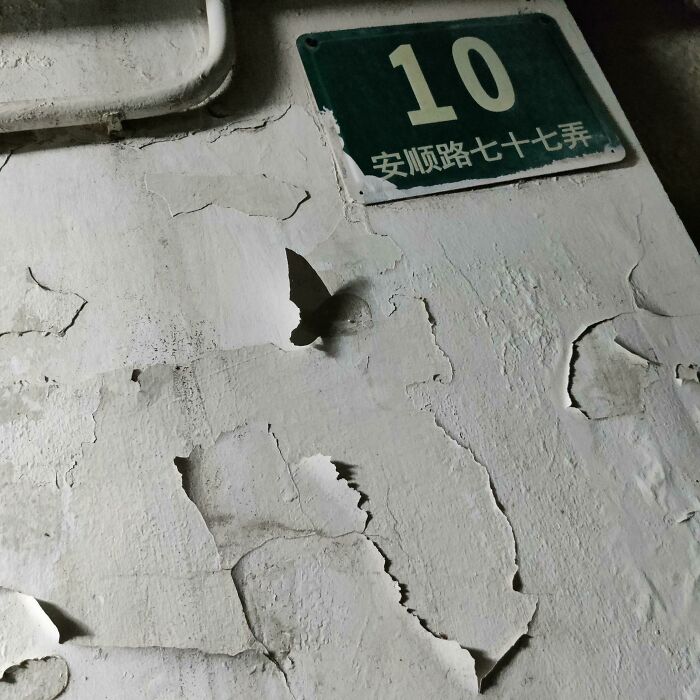 Peeling wall paint shaped like a butterfly next to street sign number 10