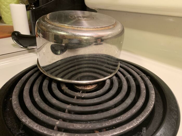 An upside-down pot on a stove burner, a photo that may need a second look to understand its perspective.