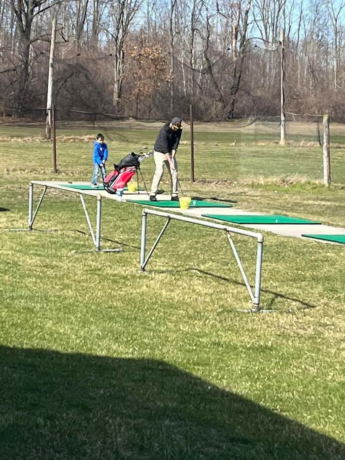 A father and son on a golf course. The photo needs a second look to understand the optical illusion.