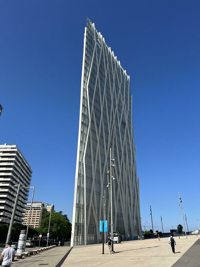 A strikingly thin, angled skyscraper against a clear blue sky, a building that makes you look twice.