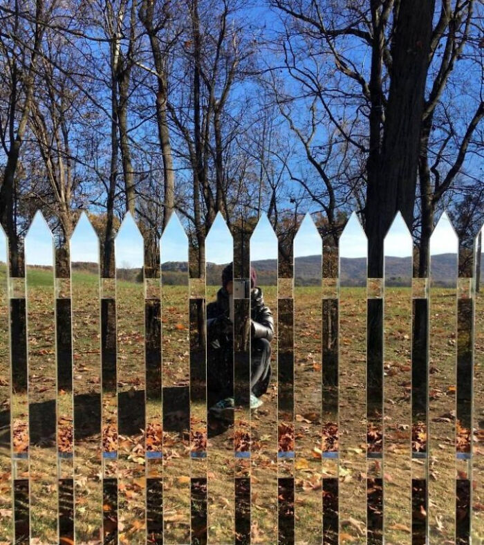 A person is reflected in a mirrored fence in a landscape, a photo you may need to look twice at.