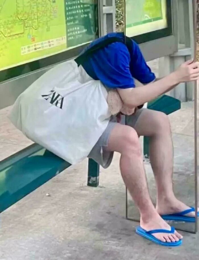 A person with their head inside a white bag and blue shirt, appearing headless, a photo you may need to look twice at.