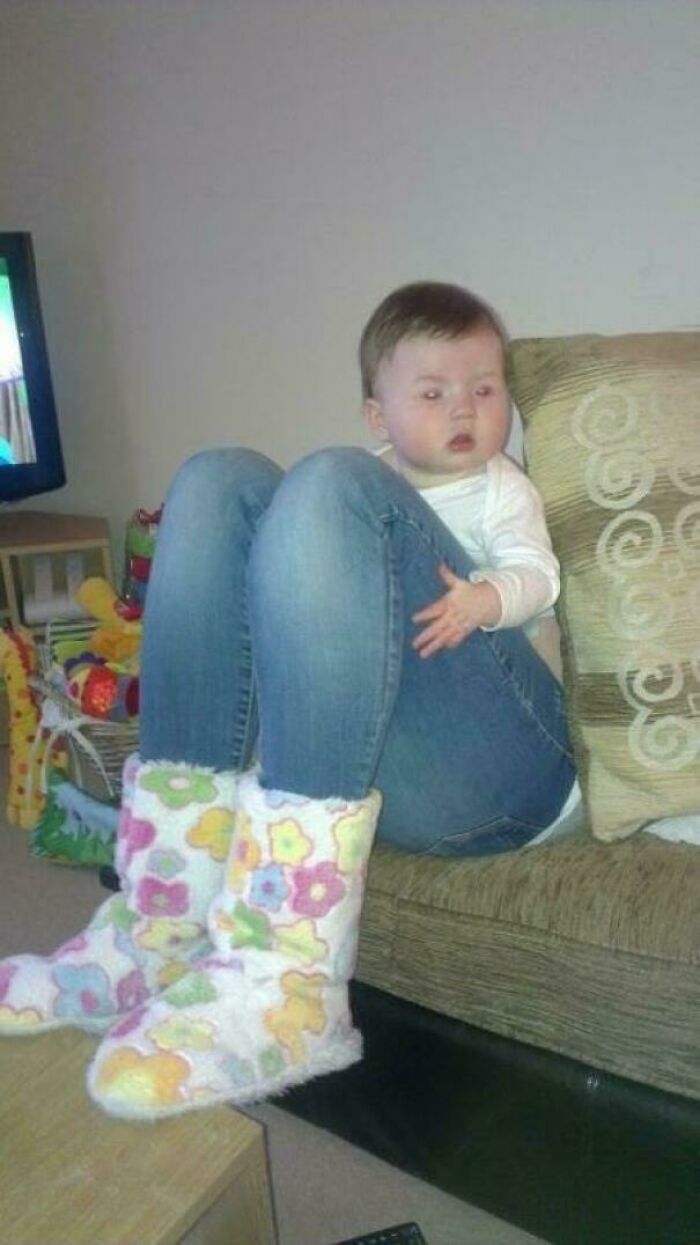 A baby with adult-sized jeans and colorful boots, creating an amusing photo that needs a second look.