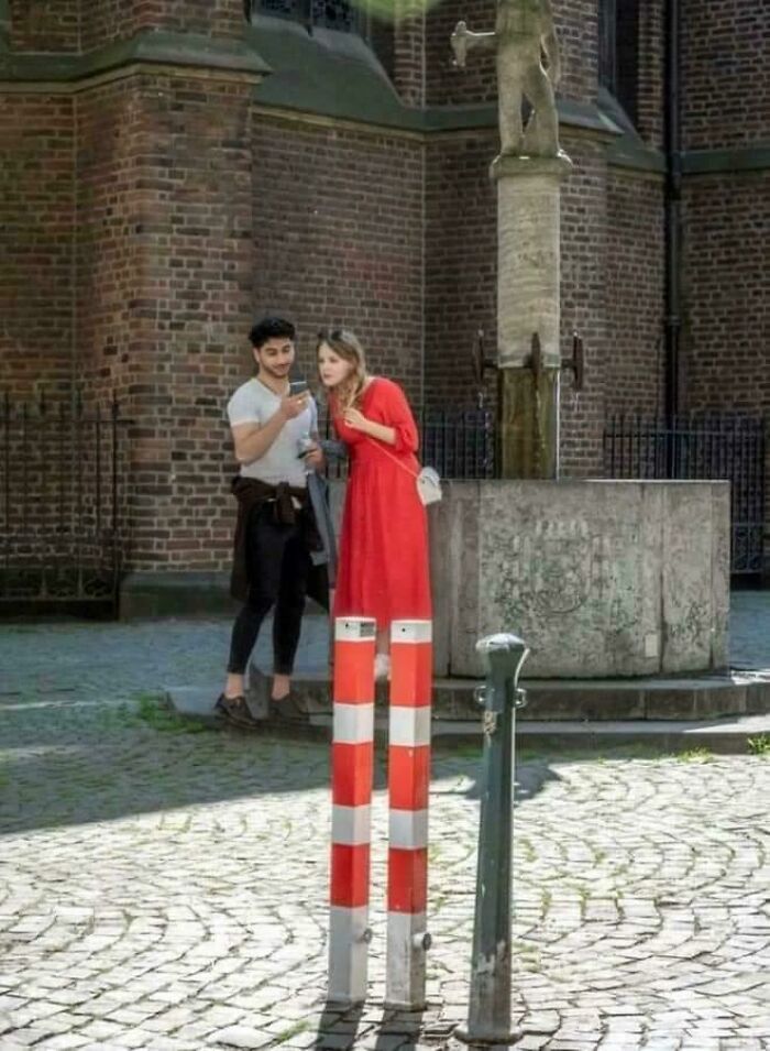 A woman appearing to have very long legs due to two red and white poles, one of the photos that need a second look.