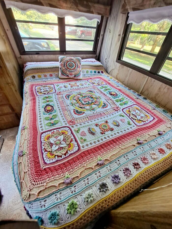 Colorful crochet blanket with floral pattern on a bed