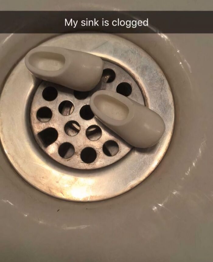 A sink drain clogged with two miniature wooden shoes, a dumb pun about clogs.