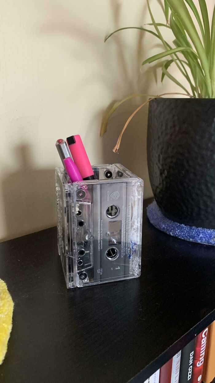 Creative desk organizer made from old cassette tapes, holding pens and highlighters.
