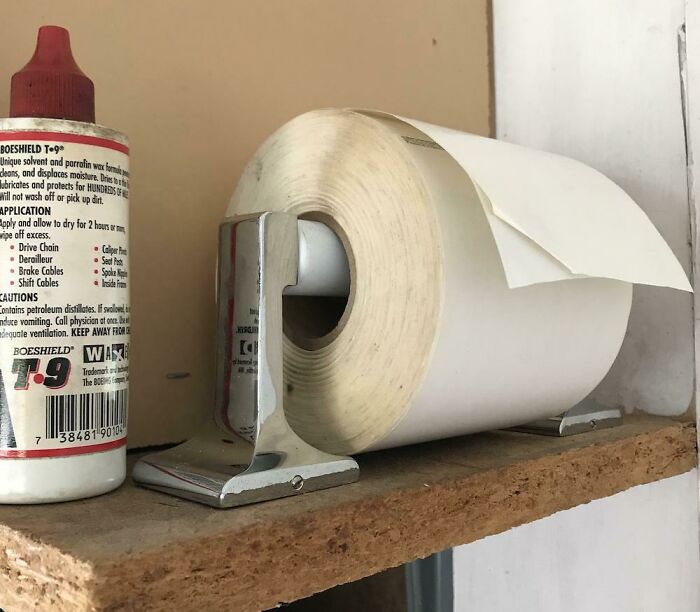 A roll of paper in a holder next to a bottle of cleaning solution. Creativity turned old junk into something worth keeping.