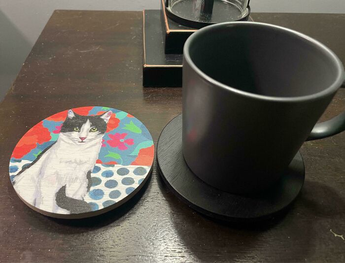 A creative coaster with a cat painting made from old junk, adding charm to a wooden table.