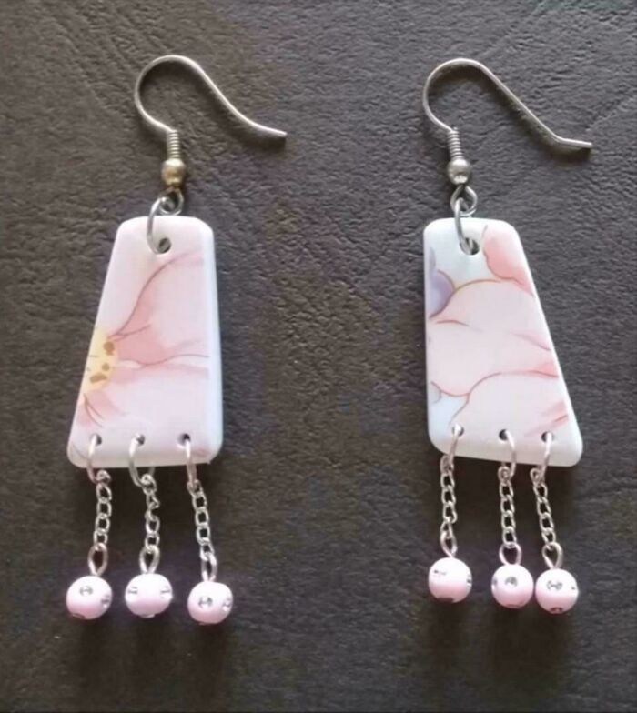 Close-up of earrings made from old junk, porcelain pieces with pink floral patterns and dangling beads.