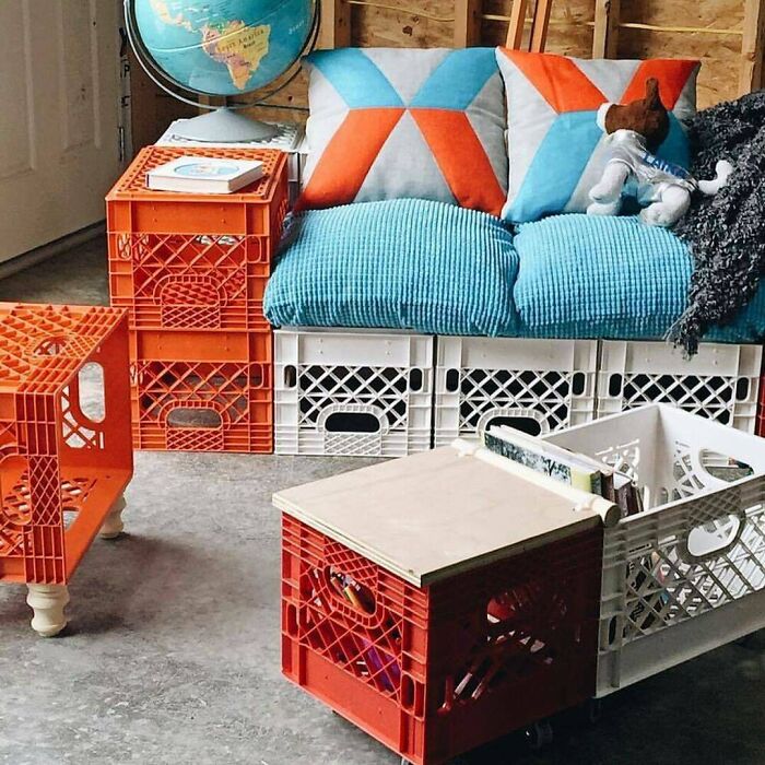 Creative use of old junk milk crates forming a colorful sofa and tables with pillows and a globe.