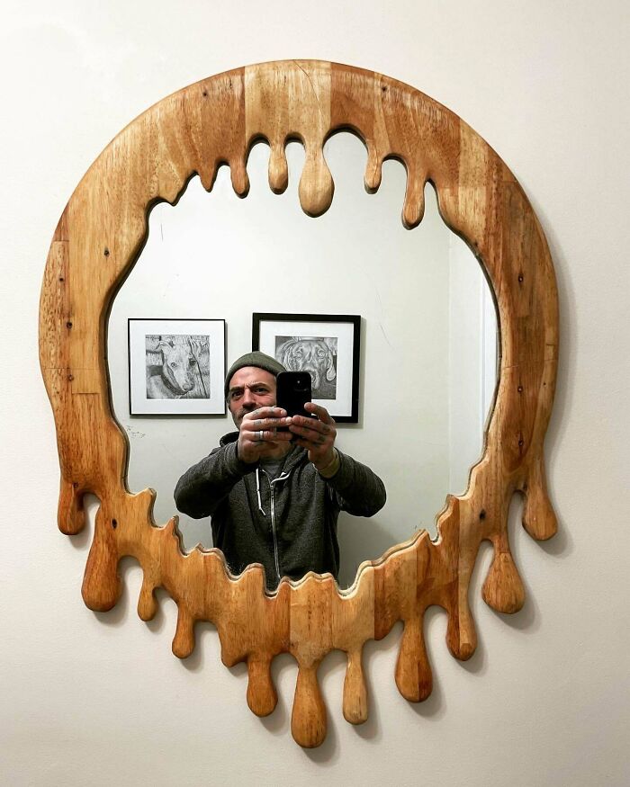 A man takes a selfie in a unique, melting-effect wooden mirror, a creative way to reuse old junk.