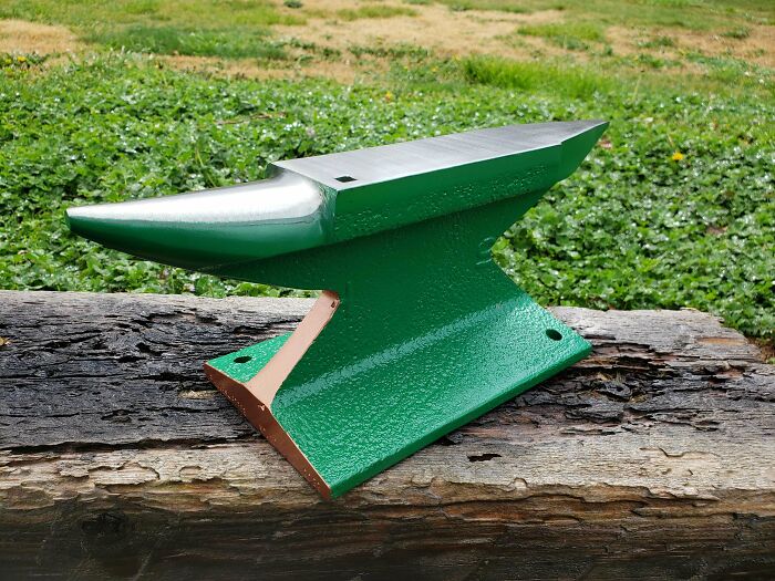 A newly painted green and copper anvil, showing how creativity can turn old junk into something worth keeping.