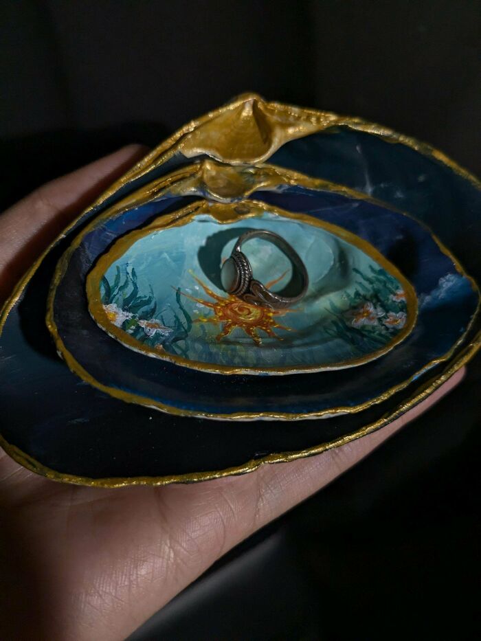 Hand holding painted seashells with a ring, showcasing creativity turning old junk into something worth keeping.
