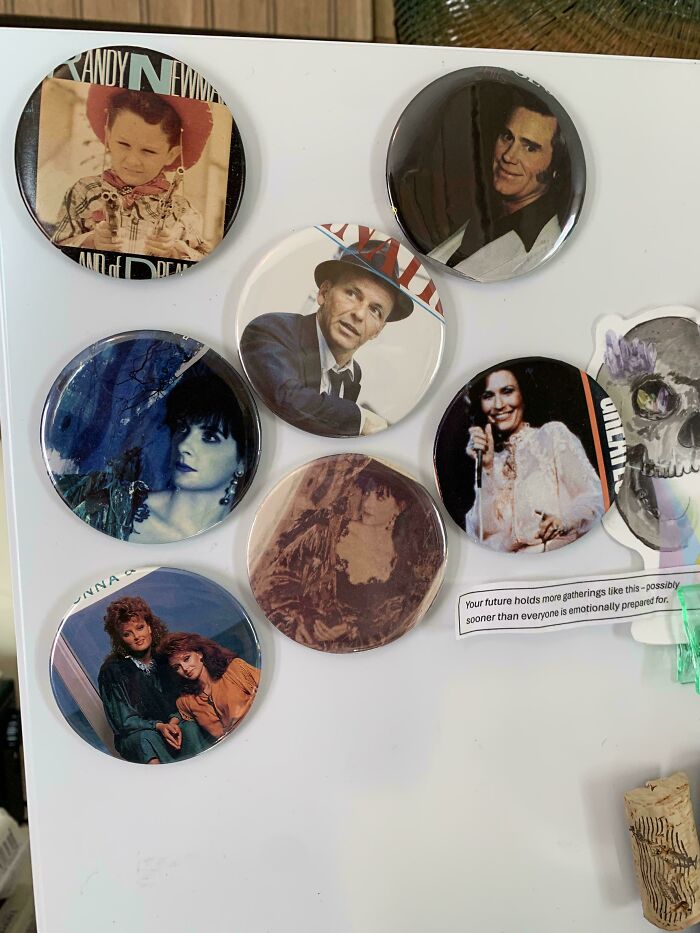 A collection of old junk buttons and magnets on a fridge, featuring music artists, repurposed creatively.