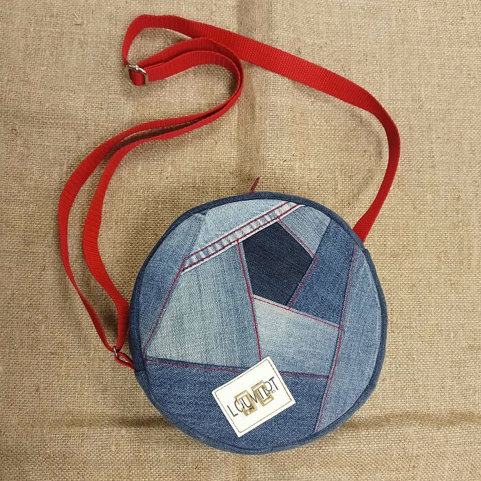 A denim patchwork handbag made from old junk, with a red strap, showing creative reuse.