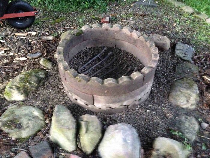 An old junk brick fire pit surrounded by stones in a garden, demonstrating creativity in outdoor design.