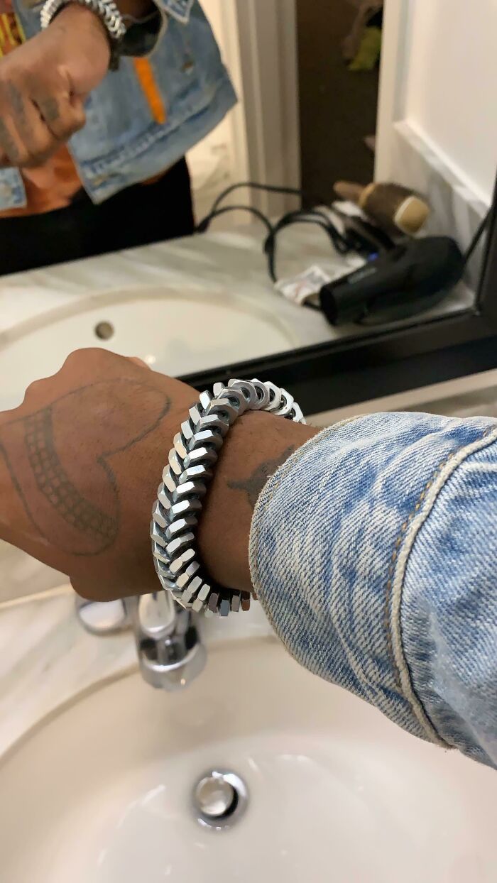 A person wearing a unique bracelet made from metal nuts, demonstrating creativity from old junk.